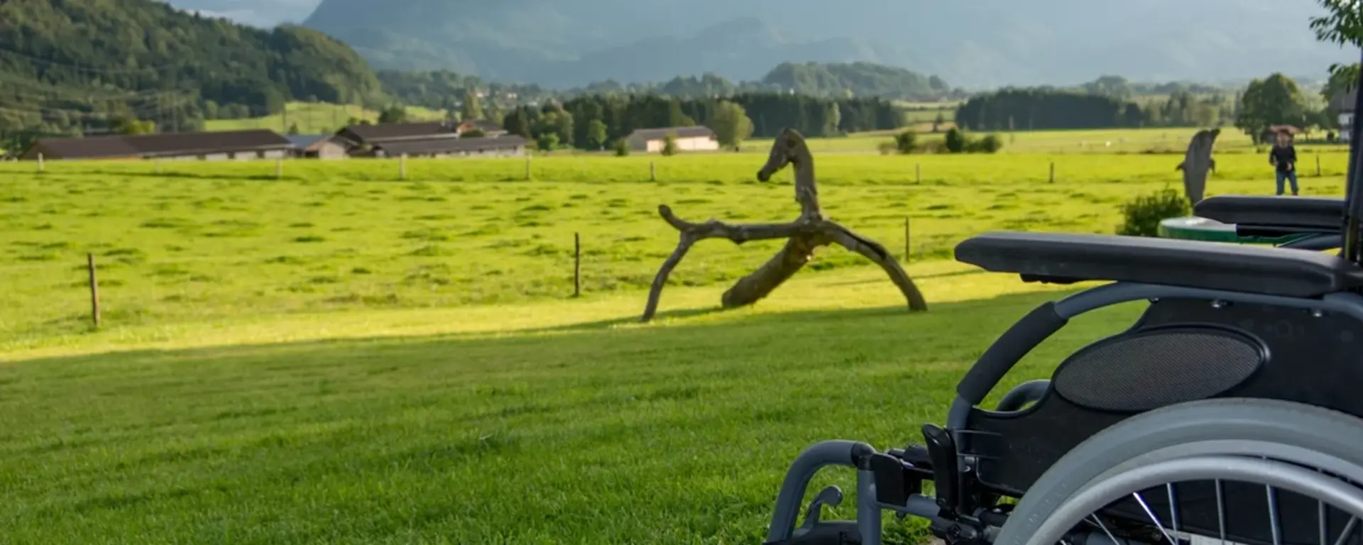 Barrierefreier Urlaub auf dem Bauernhof. Rollstuhl vor Bergpanorama